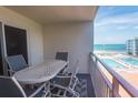 Balcony view of pool and beach with table and chairs at 4151 S Atlantic Ave # 414, New Smyrna Beach, FL 32169