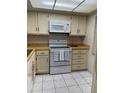 Well-lit kitchen featuring white appliances, tile flooring, and cream-colored cabinetry at 4175 S Atlantic Ave # 5280, New Smyrna Beach, FL 32169
