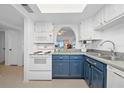 Bright kitchen features white appliances, blue cabinets, and an open view to living area at 4201 S Atlantic Ave # 402, New Smyrna Beach, FL 32169