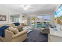 Bright living room featuring comfortable seating, a ceiling fan, a tv, and a balcony with ocean views at 4841 Saxon Dr # C201, New Smyrna Beach, FL 32169