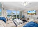 Bright living room featuring comfortable seating, a ceiling fan, a tv, and a balcony with ocean views at 4841 Saxon Dr # C201, New Smyrna Beach, FL 32169