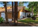 Charming home exterior featuring a brown garage door, well-manicured lawn, and mature trees at 5 Soco Trl, Ormond Beach, FL 32174