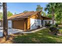 Charming home exterior featuring a brown garage door, well-manicured lawn, and mature trees at 5 Soco Trl, Ormond Beach, FL 32174