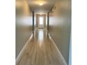 Long hallway with wood floors and neutral-colored walls leading to a door at 519 Aeolian Dr, New Smyrna Beach, FL 32168