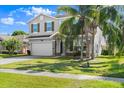 Charming two-story home with a two-car garage, complemented by lush landscaping and mature palm trees at 5337 Royal Plantation Blvd, Port Orange, FL 32128