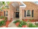 Home's brick entrance with arched features, black shutters, lush plants, and walkway at 682 Ferncliff Dr, Port Orange, FL 32127