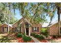Charming single-story brick home with arched windows, lush landscaping, and mature trees at 682 Ferncliff Dr, Port Orange, FL 32127