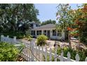 Landscaped front yard showcasing a white picket fence and mature trees at 825 E 23Rd Ave, New Smyrna Beach, FL 32169