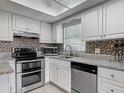 Bright kitchen features white cabinets, stainless steel appliances, mosaic tile backsplash, and natural light at 95 Moonstone Ct, Port Orange, FL 32129