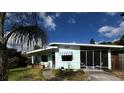 Exterior shot of the home, showcasing the facade, screen porch, and mature landscaping under a sunny sky at 114 Hickory St, New Smyrna Beach, FL 32168