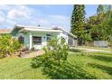 A charming home with a well-kept lawn, complemented by mature trees and a colorful garden at 114 Hickory St, New Smyrna Beach, FL 32168