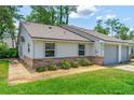 The front of a home displays a well-kept lawn, gray window frames and a gravel garden at 115 Bob White Ct, Daytona Beach, FL 32119