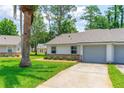 A single-story home shows a gray garage door, well-kept lawn, and small bushes at 115 Bob White Ct, Daytona Beach, FL 32119