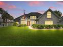 Picture-perfect home with a lush green lawn, featuring landscape lighting and a brick accent wall at 128 Godfrey Rd, Edgewater, FL 32141