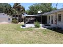 Exterior view of the home and screened-in porch, surrounded by a large yard at 1830 Needle Palm Dr, Edgewater, FL 32132
