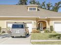 Charming beige home featuring an arched entryway, manicured lawn, and attached two-car garage on a sunny day at 1903 Turnbull Lakes Dr # 1903, New Smyrna Beach, FL 32168