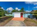 Charming single-story home with a white garage door, bright red door, and colorful landscaping at 2576 Sunset Dr, New Smyrna Beach, FL 32168