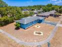 An aerial view showcases this cozy blue house, complemented by lush surrounding trees and a concrete-paved walkway at 2802 English Dr, Deltona, FL 32738