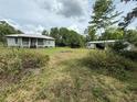Wide view of the property featuring the house, outbuilding, and lush surroundings at 3625 Pioneer Trl, New Smyrna Beach, FL 32168