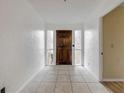 Bright foyer featuring a beautiful wood door, tile flooring, and white walls at 3718 Paige St, Port Orange, FL 32129