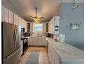 Stylish kitchen boasting white cabinetry, stainless steel appliances, and a marble countertop bar at 415 Jessamine Ave, New Smyrna Beach, FL 32169