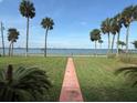 Lush lawn with palm trees offers a beautiful view of the bay, creating a serene and tropical atmosphere at 5018 Riverside Dr, Port Orange, FL 32127