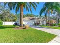 View of house showcasing a manicured lawn, mature palm trees, and two-car garage at 6088 Sabal Hammock Cir, Port Orange, FL 32128