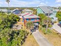 Aerial view of a charming blue two-story home with covered parking amid lush landscaping in a coastal community at 6860 Turtlemound Rd, New Smyrna Beach, FL 32169