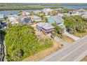 Aerial view of a charming blue two-story home with covered parking in a coastal community near a river and the ocean at 6860 Turtlemound Rd, New Smyrna Beach, FL 32169