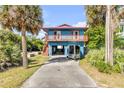 Charming blue two-story home featuring a cozy balcony, complemented by lush green foliage, and covered parking at 6860 Turtlemound Rd, New Smyrna Beach, FL 32169
