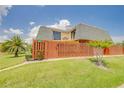 Two-story home featuring a balcony, green lawn, and a wooden privacy fence, with a number sign at 90 Cedar Dunes Dr, New Smyrna Beach, FL 32169
