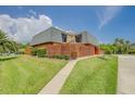 Two-story home with Mansard roof, green lawn, and balcony view, with a wooden fence, number sign, and walkway at 90 Cedar Dunes Dr, New Smyrna Beach, FL 32169