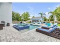 Backyard pool and spa with pavers, lounge chairs, lush landscaping, and detached guest house at 90 Cunningham Dr, New Smyrna Beach, FL 32168