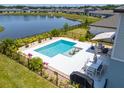 Aerial view of a backyard with a stunning pool and a relaxing patio area by the lake at 113 Pitching Wedge Dr, Daytona Beach, FL 32124