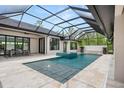 Sparkling pool with a screened enclosure and a water feature, surrounded by a travertine tile patio at 1624 Turnbull Crossings Dr, New Smyrna Beach, FL 32168