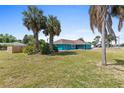 Turquoise home exterior featuring lush palms, a long covered patio, and a freshly mowed lawn at 1845 Willow Oak Dr, Edgewater, FL 32141
