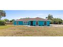 Turquoise home with a charming entrance featuring arched windows, a dark screen door, and minimal landscaping at 1845 Willow Oak Dr, Edgewater, FL 32141