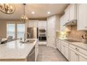 Beautiful kitchen with white cabinetry, stainless steel appliances, an island with a sink, and stylish lighting at 219 Venetian Palms Blvd, New Smyrna Beach, FL 32168