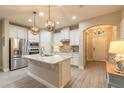 Open kitchen with stainless steel appliances, granite countertops, a center island with a sink, and pendant lighting at 219 Venetian Palms Blvd, New Smyrna Beach, FL 32168