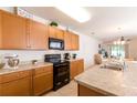 Well-lit kitchen with wood cabinets, black appliances, and a view of the dining area at 2818 Taton Trce, New Smyrna Beach, FL 32168