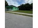 Exterior shot of green house featuring a charming covered porch and ample green space at 306 Sheldon St, New Smyrna Beach, FL 32168