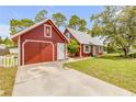 Charming red home with matching detached garage with lush greenery and a quaint yard at 3222 Juniper Dr, Edgewater, FL 32141