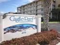 Castle Reef Condominiums sign with landscaped bushes and a palm tree near the street at 4175 S Atlantic Ave # 2280, New Smyrna Beach, FL 32169