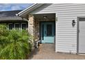 Close-up of a home's stone accented entrance, featuring a light blue door, outdoor bench, and brick pathway at 475 Spruceview Dr, Port Orange, FL 32127