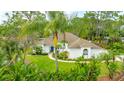 Inviting one-story home with a well-manicured lawn and tropical landscaping around the house at 484 Sweet Bay Ave, New Smyrna Beach, FL 32168