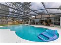 Large screened-in pool with blue water and an inflatable float; view of house at 484 Sweet Bay Ave, New Smyrna Beach, FL 32168