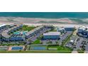Aerial view showing a condo complex with pools, beach access, parking, and tennis courts at 4849 Saxon # C202, New Smyrna Beach, FL 32169