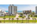 View of a building across a beachfront road featuring palms and beach access at 5300 S Atlantic Ave # 1-603, New Smyrna Beach, FL 32169