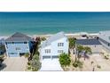 Aerial view of a charming light blue beach house, complemented by lush landscaping and ocean views at 6871 S Atlantic Ave., New Smyrna Beach, FL 32169