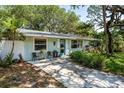 Inviting single story home featuring a quaint front patio with seating, surrounded by lush trees and foliage at 804 E 12Th Ave, New Smyrna Beach, FL 32169